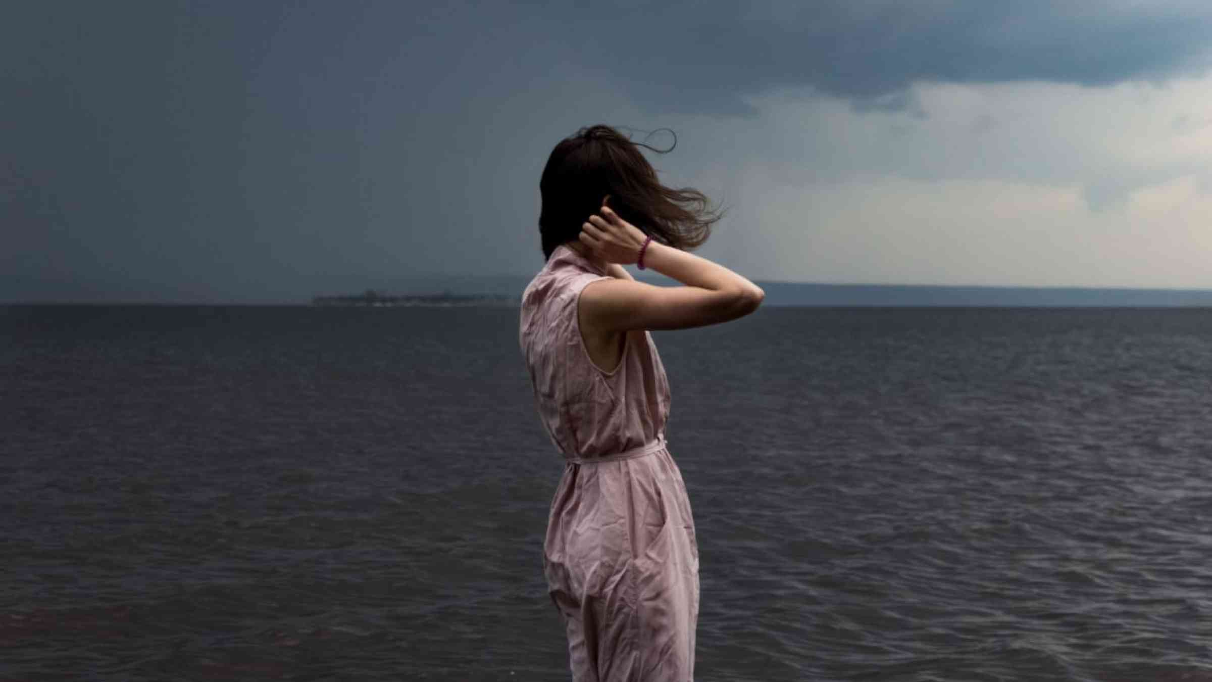 Woman standing on the shore during a storm.