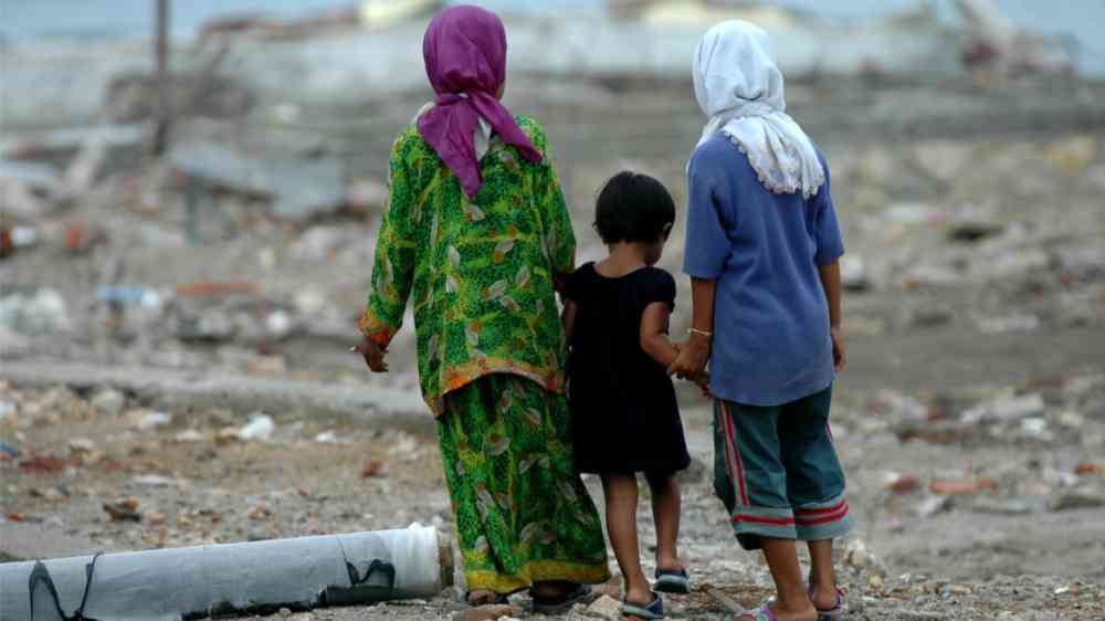 Three girls walking on the site of the 2004 Indonesia tsunami