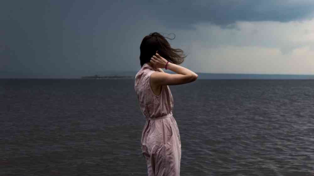 Woman standing on the shore during a storm.