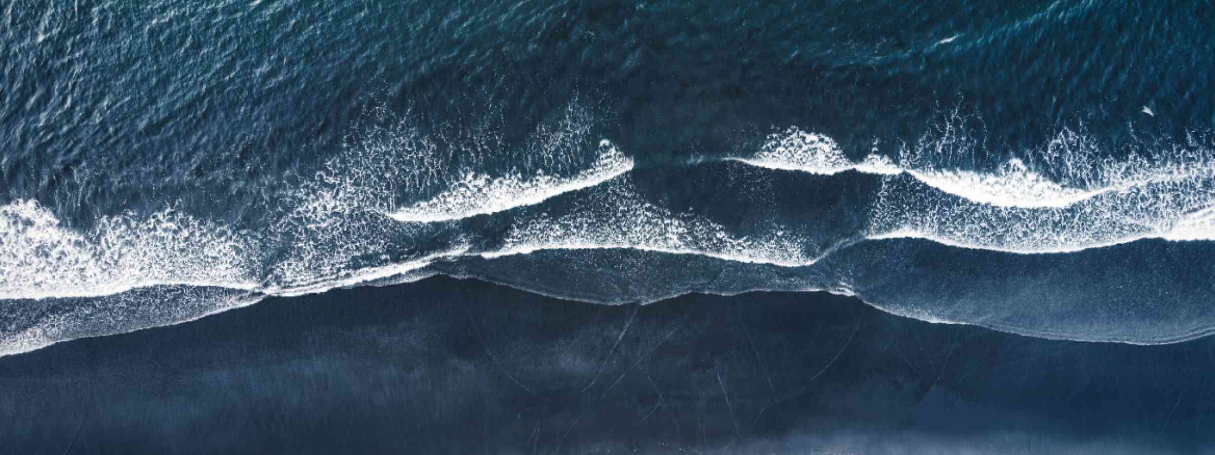 Wave tsunami sea ocean Aerial drone view of a moody atlantic ocean wave on a black sand beach during summer in Iceland